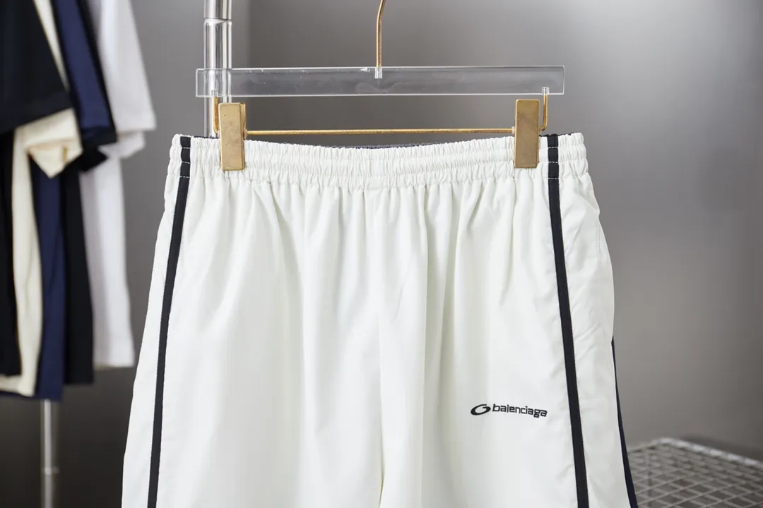 Balenciaga 𝘽𝘼𝙇𝙀𝙉𝘾𝙄𝘼𝙂𝘼 BLCG 25SS double-split waterproof sports pants. Light luxury. A must-have item for daily commuting for men and women. Correct version. Welcome to compare. Detailed features · Customized matt Taslan jacket fabric · The entire fabric is pre-treated with a waterproof coating · The interior is made of three-level polyester bird's eye mesh · OS ultra-loose silhouette design · Side pockets · Elastic waistband design · Contrast color Black webbing splicing · Front and rear contrast color splicing and cutting design · Imported Tajima machine embroidery ring logo · Original main mark washed tag brand packaging Color: White/Royal Blue Size: 46/48/50/52